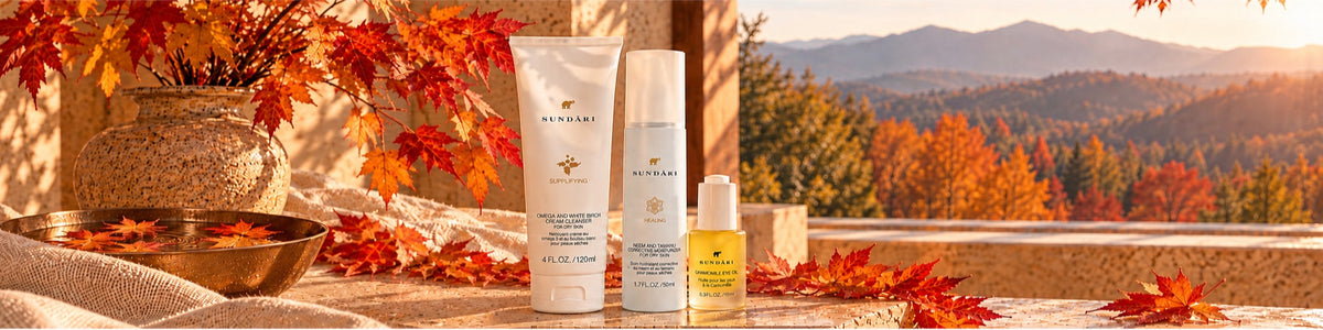 SUNDÃRI cleanser, Neem and Tamanu moisturizer and Chamomile Eye Oil beside a bronze bowl of water with floating autumn leaves on a sunlit terrace